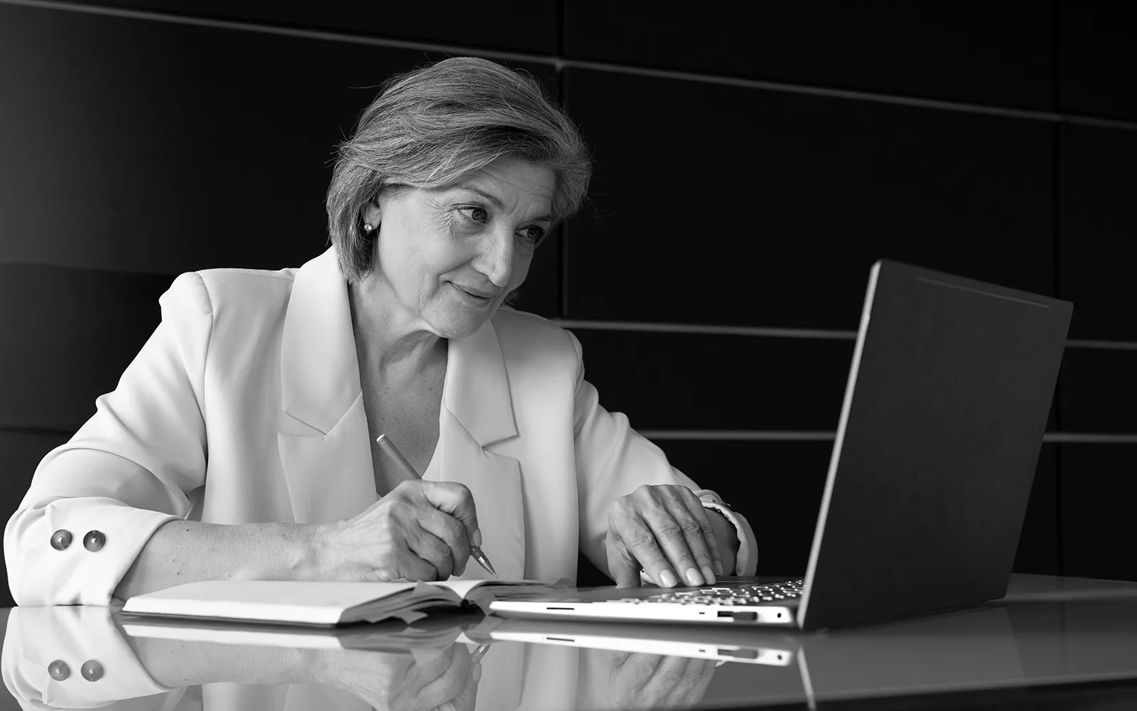 Author working thoughtfully with notebook and laptop