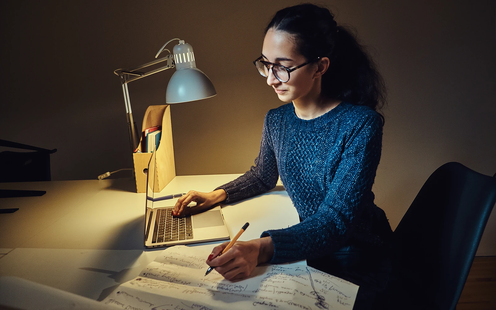 Editor reviewing a manuscript beside a laptop